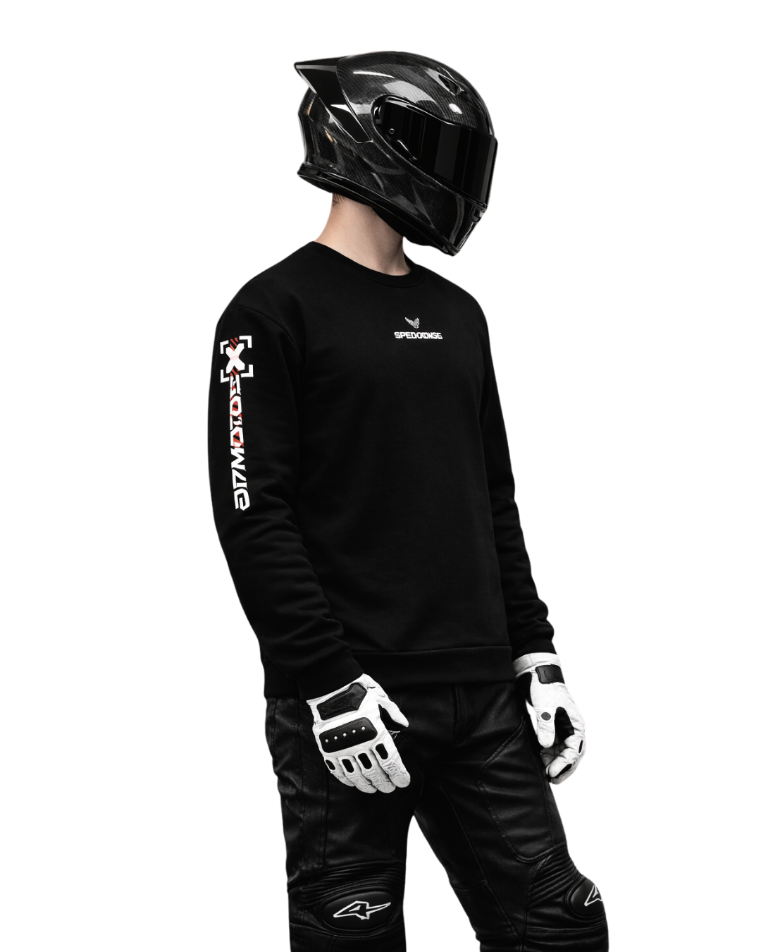 Motorcycle rider wearing black streetwear sweatshirt and carbon full-face helmet, standing in dark studio setting, motorsport lifestyle focused on speed, control, and performance.