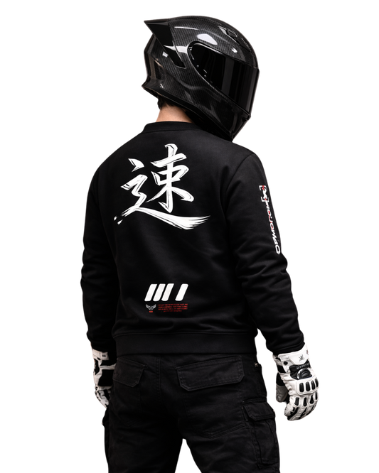 Motorcycle rider wearing black streetwear sweatshirt with bold back graphic and carbon full-face helmet, photographed from behind in dark studio, motorsport culture and speed-driven lifestyle.